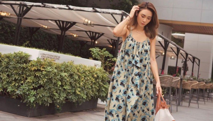 Wanita mengenakan gaun floral midi, tampil stylish dengan latar belakang musim panas.